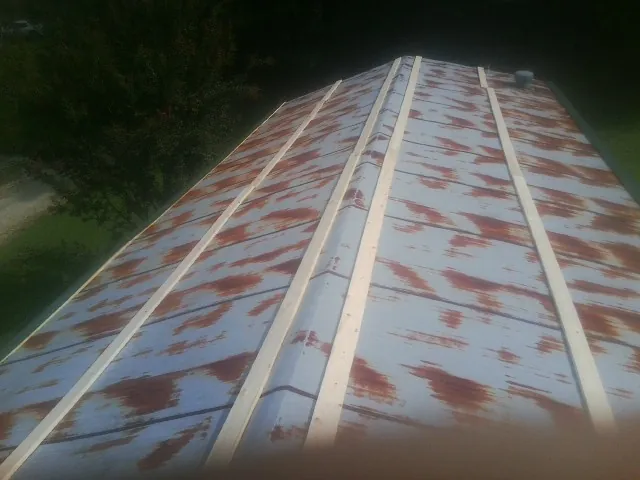 Rusted metal roof panels with new wood purlins before replacement — Storm Damage Roof Repair in Thompson by Roofing Brothers
