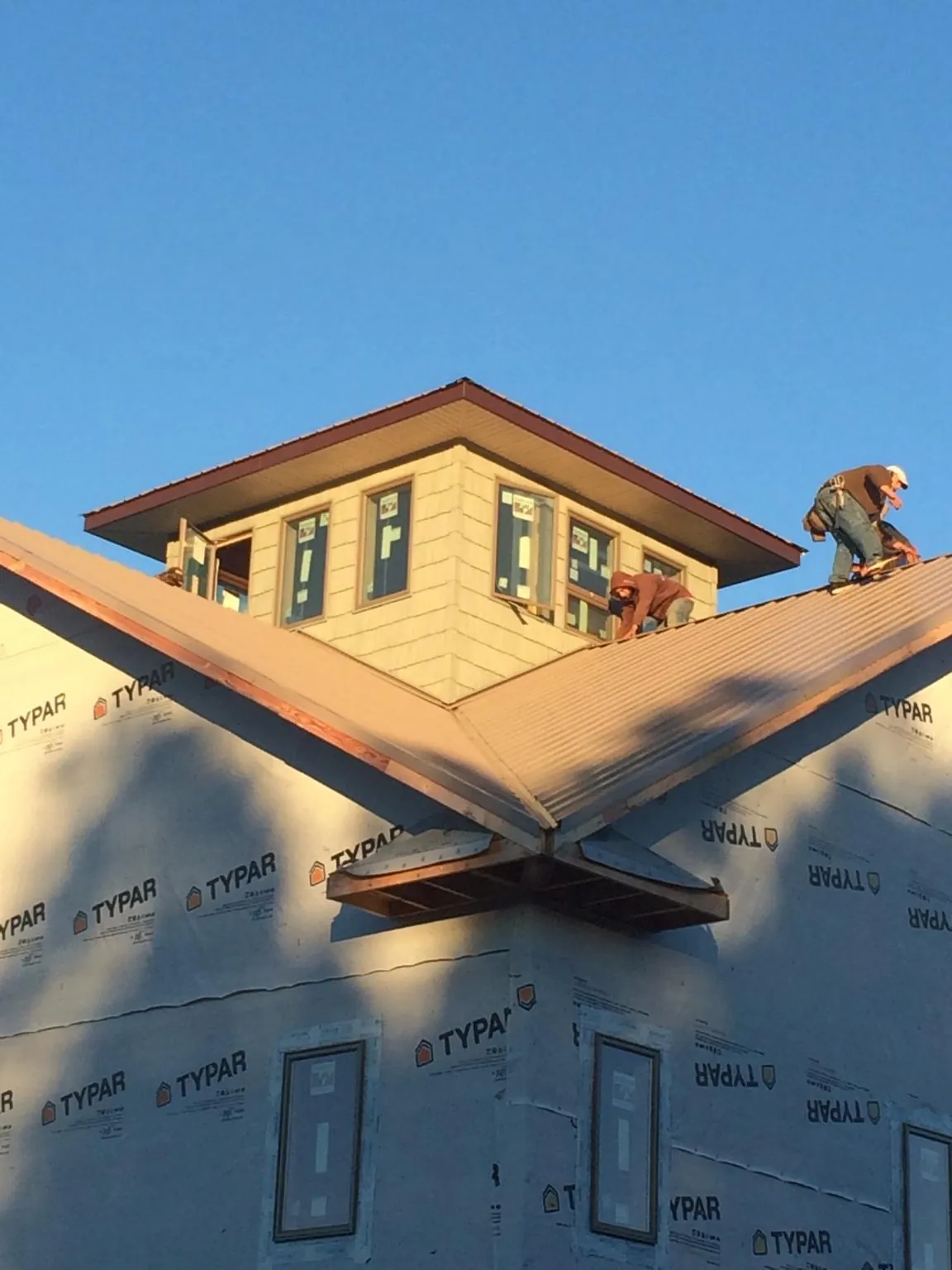 Roofers working around a rooftop cupola on a new metal roof at sunset — Roof Waterproofing in Thompson by Roofing Brothers